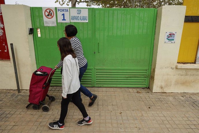 Una niña y una mujer pasan delante de un colegio cerrado en Alaquàs (Valencia).