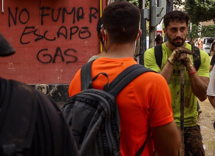 Dos personas junto a un aviso de "no fumar, escape de gas", en Sedaví.