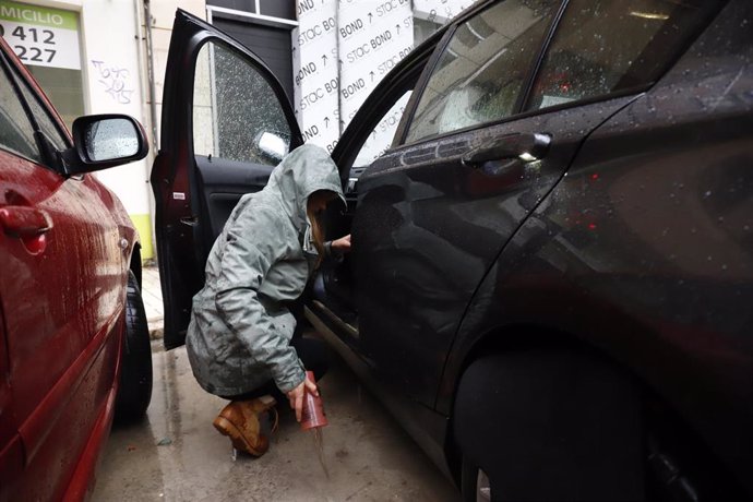 Una mujer achica el agua del interior de su vehículo tras las fuertes lluvias que azotan en la capital.