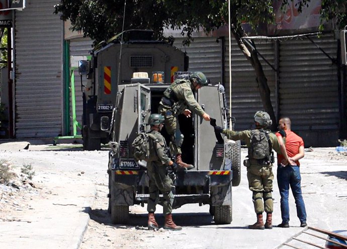 Archivo - Militares israelíes detienen a un ciudadano palestino en un campo de refugiados en Cisjordania