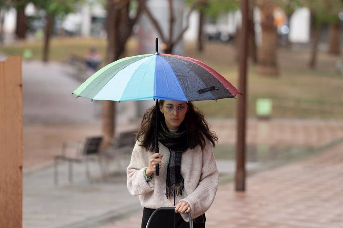 Archivo - Una joven camina con un paraguas, a 12 de mayo de 2023, en Barcelona, Catalunya (España). Casi todas las comarcas de Catalunya estarán pendientes hoy de una nueva tanda de chubascos y tormentas como consecuencia de la irrupción de una masa de ai