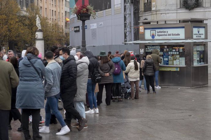 Archivo - Varias personas hacen cola en una administración de Loterías 