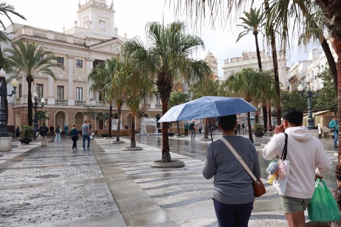 Varias personas con paraguas en la ciudad de Cádiz, en alerta naranja por fuertes lluvias.