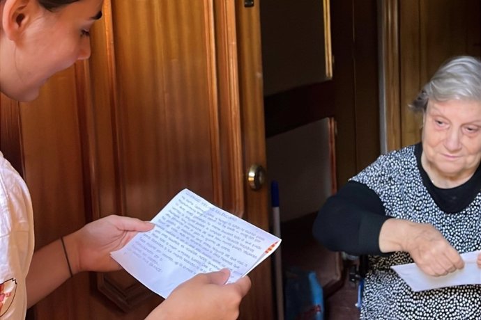 Una voluntaria lee una carta de 'Letras de esperanza' a una vecina afectada por la DANA.