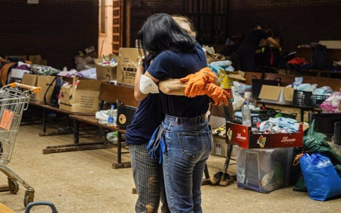 Dos personas se abrazan durante la distribución de recursos a la población afectada por la DANA en Valencia.