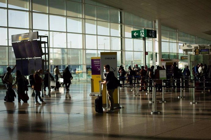 Archivo - Varios pasajeros con maletas en el aeropuerto en la T1 del Aeropuerto de Barcelona-El Prat.