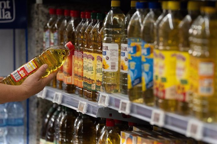 Archivo - Una persona coge una botella de aceite en un supermercado