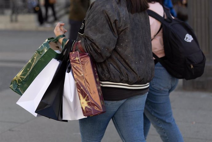 Archivo - Una persona lleva varias bolsas de compra durante Black Friday de 2023.