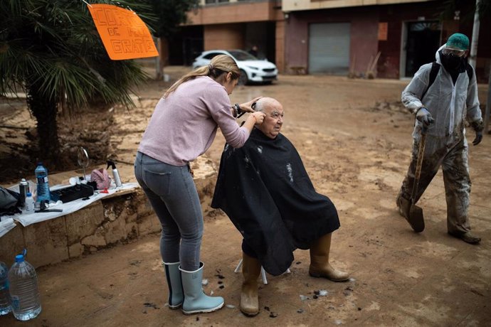 Una mujer corta el pelo a un vecino de Paiporta