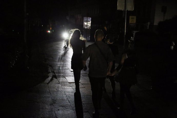 Archivo - July 4, 2024, Odessa, Ukraine: The light from the car headlights illuminates people walking along the dark Lanzheronovskaya street. Electricity shortage due to damage to power plants and distribution equipment as a result of Russian shelling thr