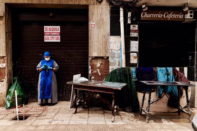 Una monja junto a varias sotanas tendidas para secarse tras la DANA