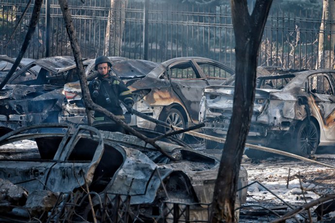 18 November 2024, Ukraine, Odesa: An Ukrainian rescuer stands amidst burnt-out cars in the courtyard of a residential building following a Russian missile attack. The death toll from the strike has risen to 10, with 43 others wounded, according to Ukraine