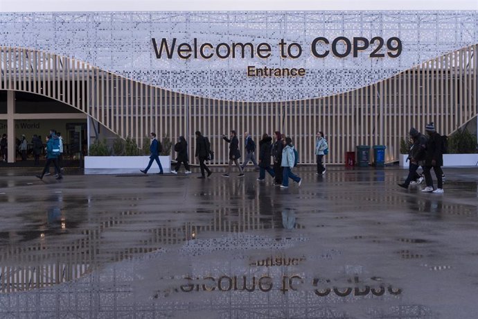 HANDOUT - 14 November 2024, Azerbaijan, Baku: Participants walk in front of a main entrance during the United Nations Climate Change Conference COP29 