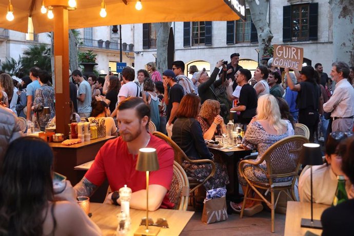 Archivo - Varias personas en una terraza durante una manifestación contra la masificación turística.