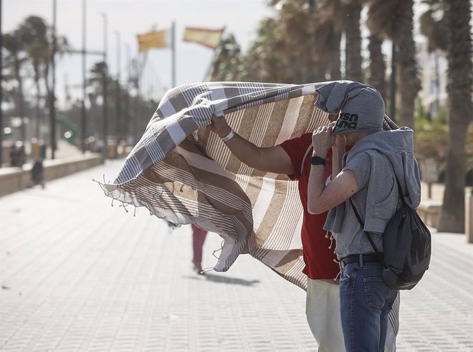 Archivo - Arxiu - Dos persones es refugien del vent al passeig de la platja de la Malvarrosa en imatge d'arxiu