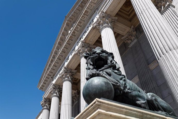 Archivo - Uno de los emblemáticos leones que se encuentran delante de la fachada del Congreso de los Diputados en la Plaza de las Cortes de Madrid.