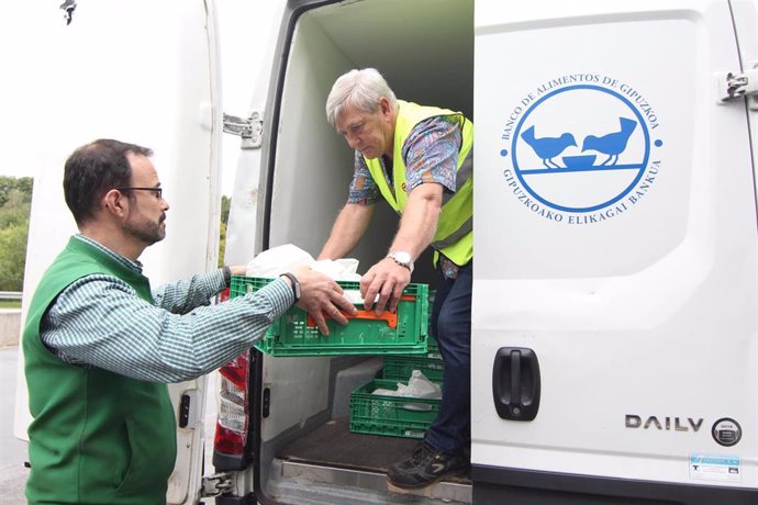 Un trabajador de la empresa de distribución ayuda a un operario del Banco de Aimentos a cargar alimentos en un camión