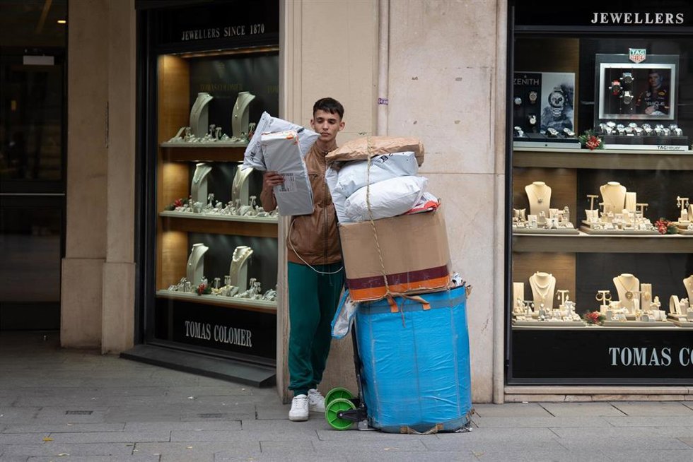 Archivo - Un joven se apoya junto a cajas con compras durante la campaña de Navidad