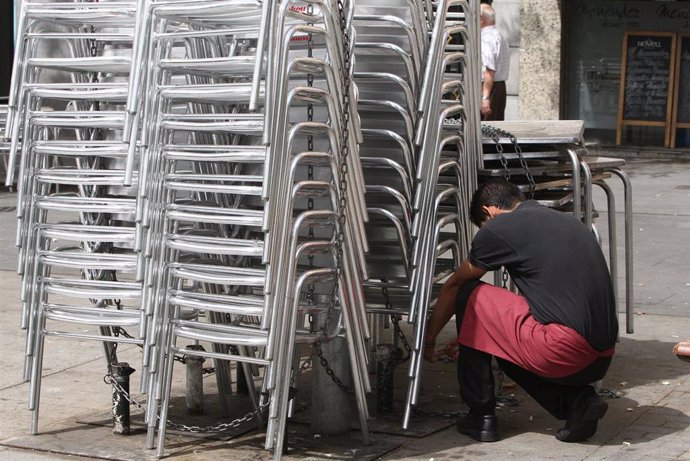 Archivo - Un camarero se dispone a colocar las sillas de la terraza de un bar