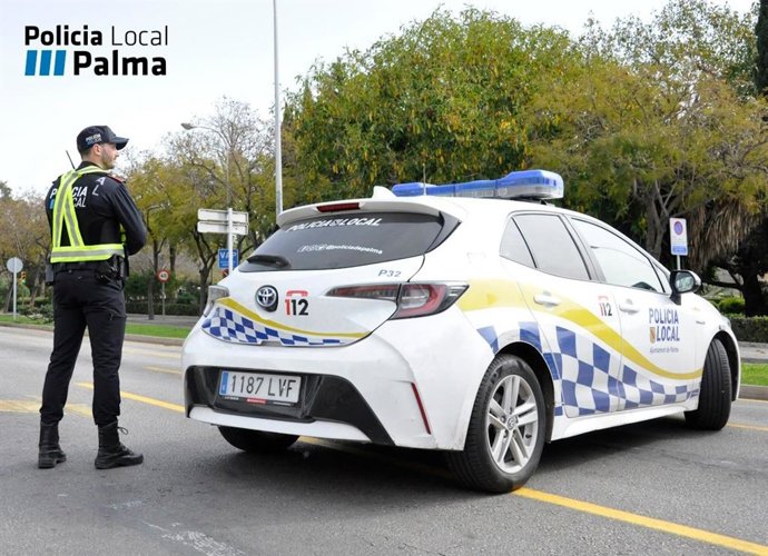 Agente de la Policía Local de Palma junto a un coche patrulla.