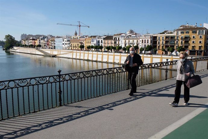 Archivo - Dos personas pasean por el puente de Triana, en Sevilla (Andalucía, España)