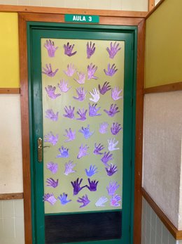 Puerta decorada con huellas de manos moradas como símbolo de rechazo a la violencia de género.