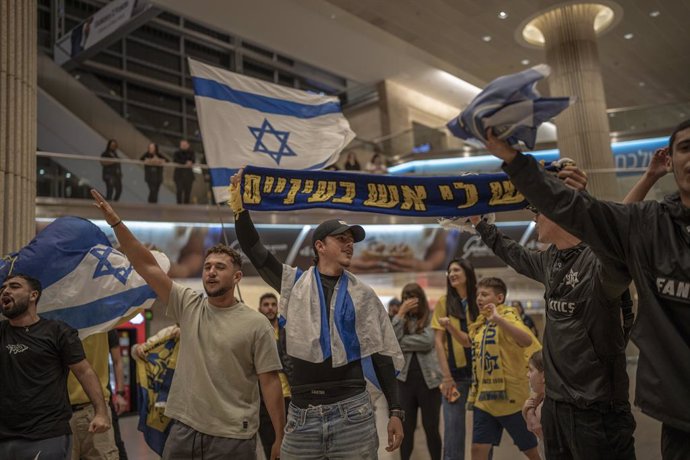 08 November 2024, Israel, Lod: Maccabi Tel Aviv fans wave flags as they arrive at Ben Gurion airport on a flight from Amsterdam. Israeli soccer fans were attacked by pro-Palestinian demonstrators before the UEFA Europa League soccer match between Ajax Ams