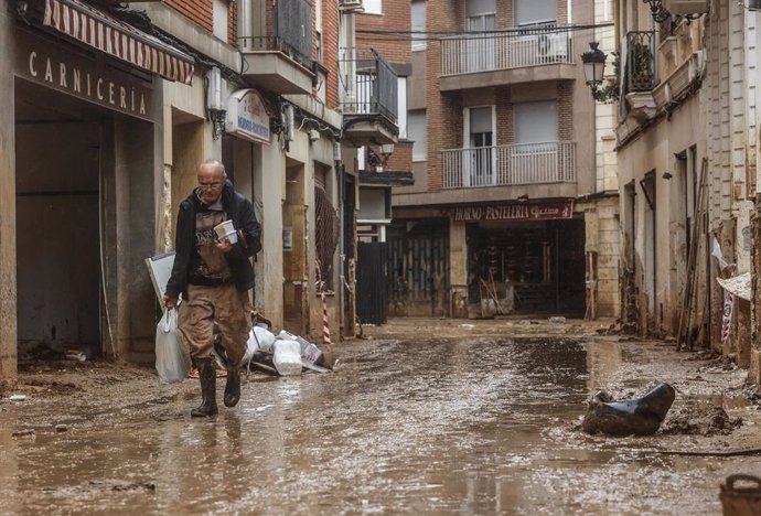 Un hombre pasea por la calle anegada de barro, a 13 de noviembre de 2024, en Paiporta, Valencia.