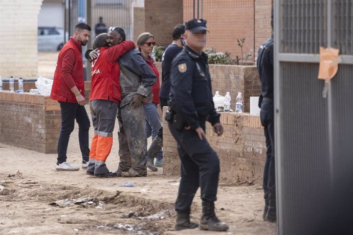 Una trabajadora de la Cruz Roja abraza a un vecino de Massanassa junto al colegio Luis Vives tras el derrumbe del porchado.