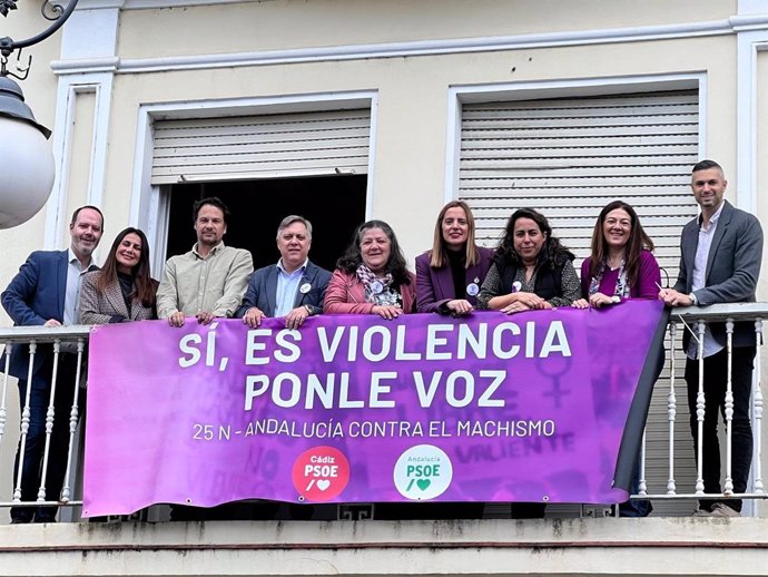 Dirigentes del PSOE en Cádiz ante la pancarta desplegada en la sede del partido por el 25N.