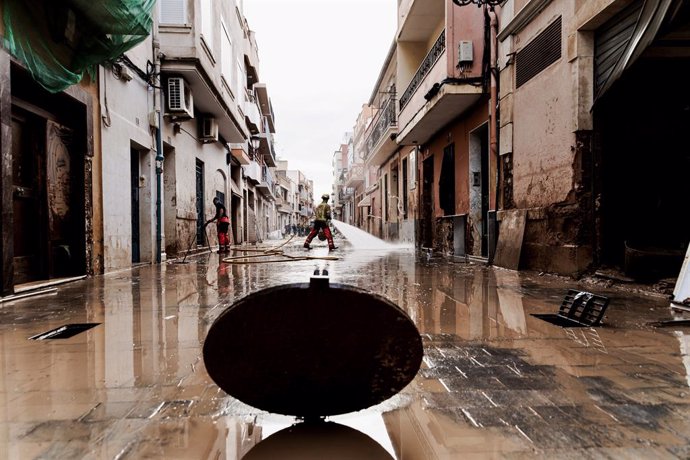 Un bomber neteja un carrer en una zona afectada per la DANA. 