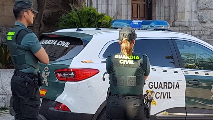 Una agente y un coche de la Guardia Civil.