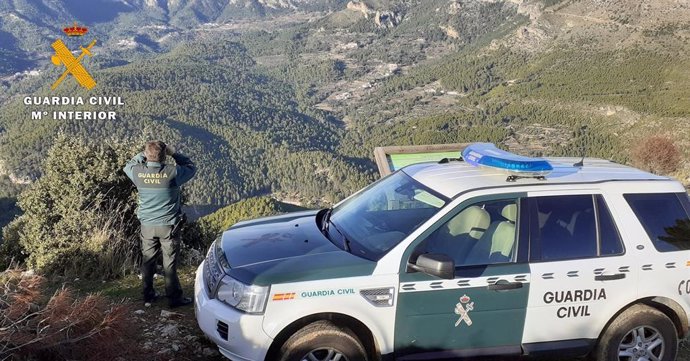 Agente de la Guardia Civil junto a su vehículo en el campo.