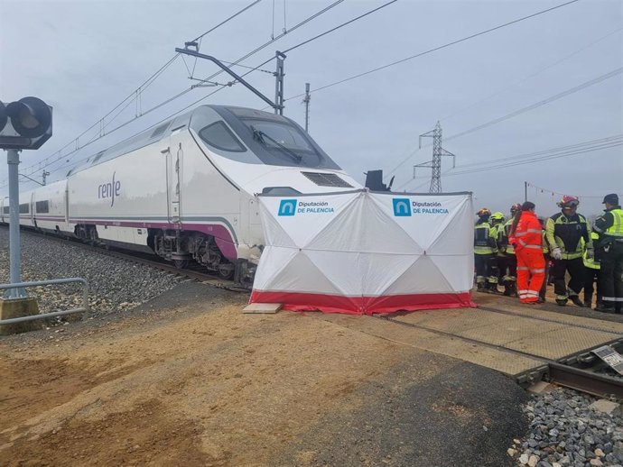 Autoridades y servicios de emergencia intervienen en el lugar del accidente por una colisión entre un tren y un vehículo en un paso a nivel en Husillos (Palencia).