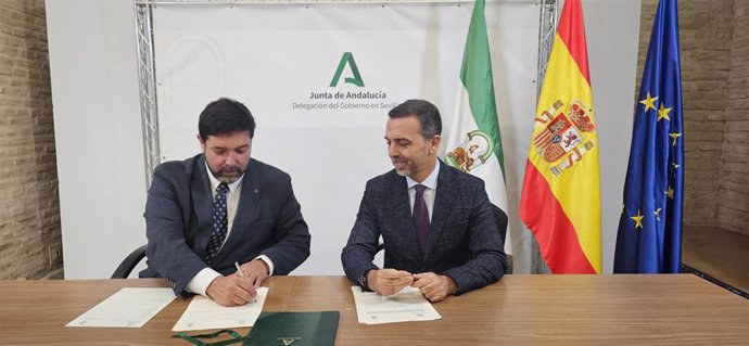 Firma entre el delegado territorial de Justicia, Administración Local y Función Pública, Javier Millán, y el alcalde de Lora del Río, Antonio Miguel Enamorado.