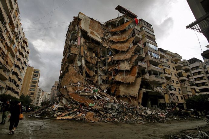 25 November 2024, Lebanon, Beirut: A woman passes by a devastated building that was targeted in an Israeli air strike in the area of Tayouneh on the outskirts of Beirut southern suburb. Renewed Israeli air strikes pounded Beirut southern suburb, after hea