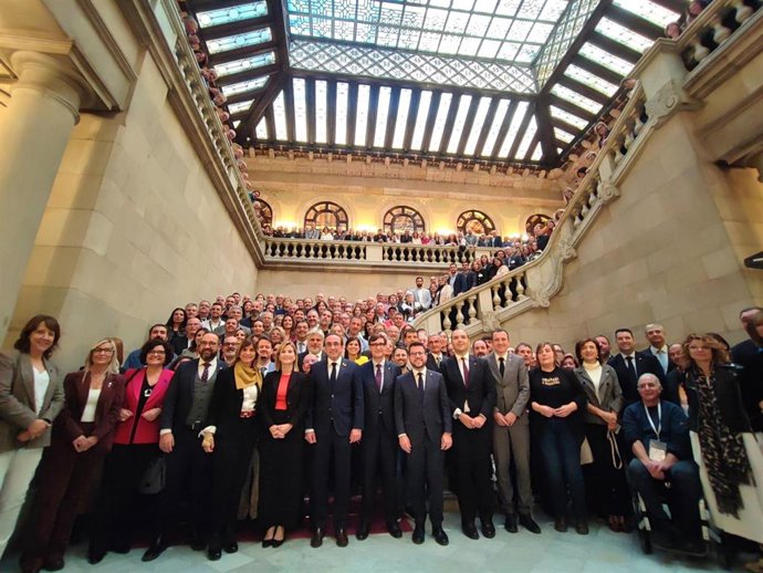 El presidente de la Generalitat, Salvador Illa; el presidente del Parlament, Josep Rull; los consellers Albert Dalmau y Òscar Ordeig, y el expresidente Pere Aragonès y otros representantes junto a entidades municipalistas en el Parlament
