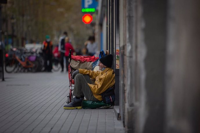 Archivo - Una persona sin techo permanece en el suelo de una calle. Archivo.