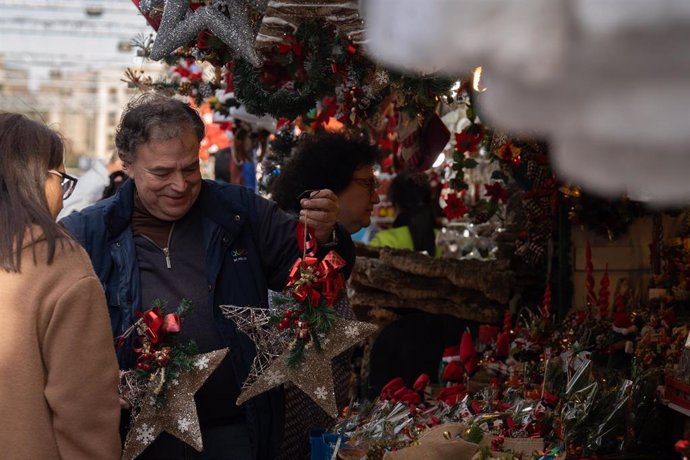 Archivo - Un hombre atiende en su puesto del mercadillo navideño, en la Fira de Santa Llúcia de Barcelona, en la plaza de la Catedral, a 30 de noviembre de 2023, en Barcelona, Catalunya (España).