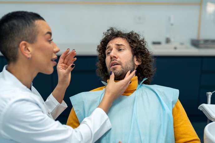 Dentista previniendo a un paciente sobre el dolor que puede sentir.