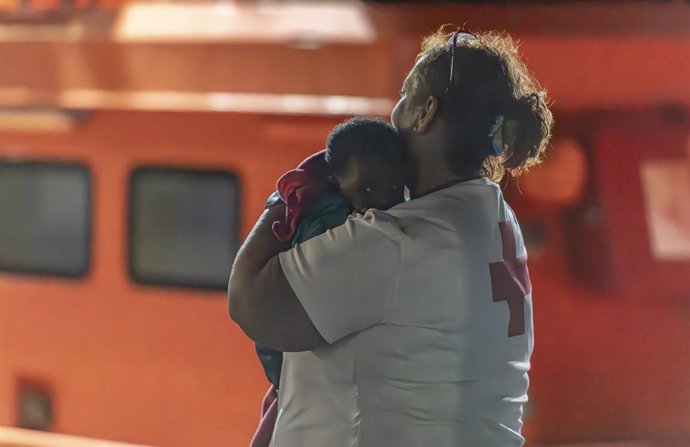 Una trabajadora de Cruz Roja con un bebé que ha llegado en la Guardamar Talía al puerto de la Restinga de El Hierro