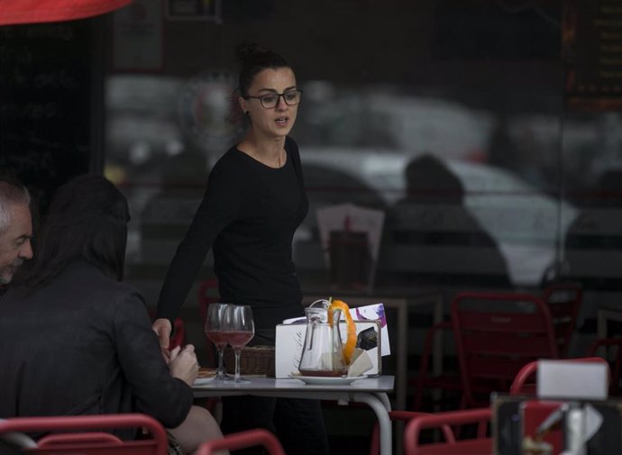 Archivo - Imágenes de recurso de una camarera atiende la mesa de un bar en Sevilla.