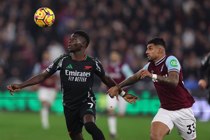 30 November 2024, United Kingdom, London: Arsenal's Bukayo Saka (L) and West Ham United's Emerson Palmieri battle for the ball during the English Premier League soccer match between West Ham United and Arsenal at the London Stadium. Photo: Chris Radburn/P