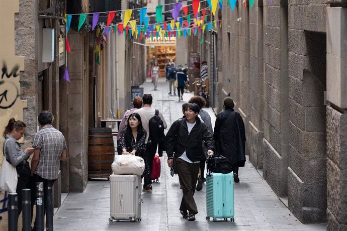 Archivo - Varios turistas con maletas en el centro de Barcelona.