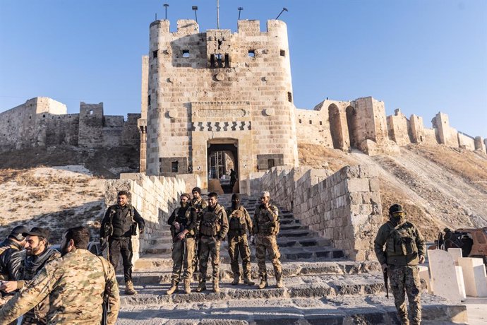 30 November 2024, Syria, Aleppo: Members of the Syrian armed opposition forces stand in front of the Ancient Castle of Aleppo after seizing control of most parts of Syria's second largest city. Photo: Anas Alkharboutli/dpa