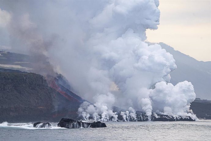 Archivo - Una persona observa la colada de lava a su llegada al mar en La Palma