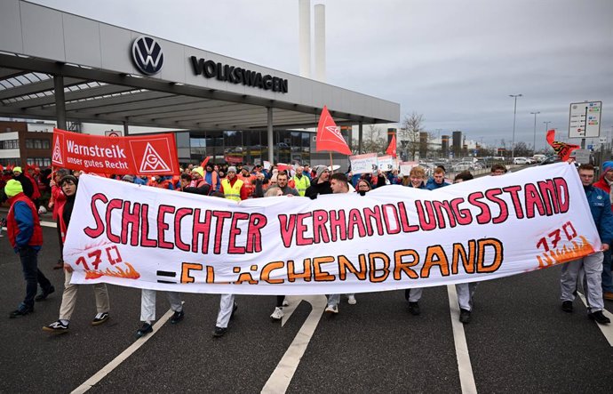 Los empleados de Volkswagen hacen una huelga de advertencia frente a la planta de Zwickau tras una pancarta con el lema "Malas negociaciones = incendio forestal".