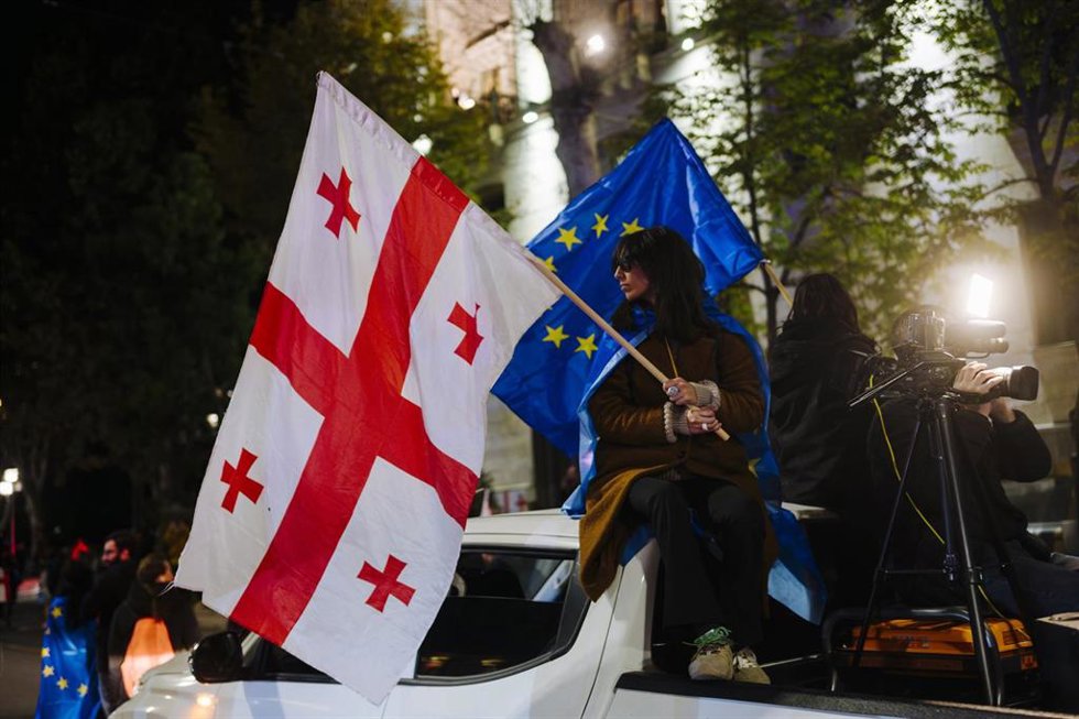 Una manifestante alza una bandera de Georgia y otra de la Unión Europea en una protesta en Tiflis
