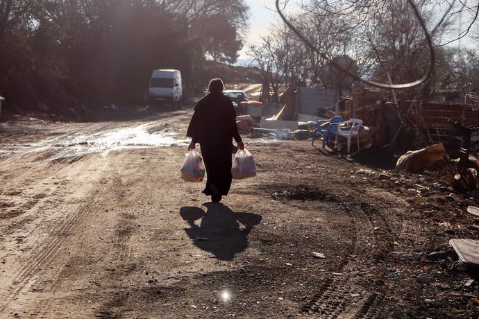 Archivo - Una mujer camina con bolsas que ha recogido en la entrega de regalos y alimentos organizada por la Fundación Madrina, en la Cañada Real, a 31 de diciembre de 2021, en Madrid, (España). La entrega de regalos y comida va dirigida para los niños de