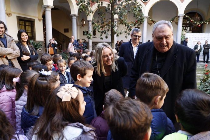 La alcaldesa de Granada, Marifrán Carazo, y el arzobispo, José María Gil Tamayo, con los escolares que han participado en la apertura del belén municipal, con el edil de Cultura, Juan Ramón Ferreira, al fondo en la imagen